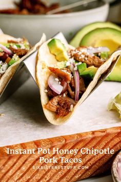 three tacos sitting on top of a cutting board next to sliced avocado