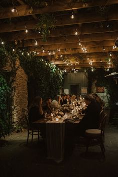 a group of people sitting around a table with candles in front of them at night