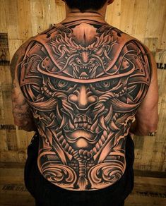 the back of a man's body is covered in tattoos and designs, including an elaborate