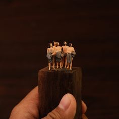 small figurines are placed on top of a piece of wood in front of a dark background