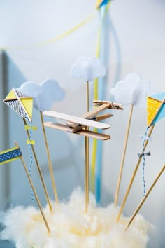 there are many small flags on sticks in the shape of airplanes and clouds, with one plane flying above them