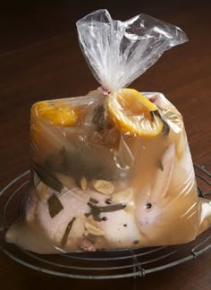 a plastic bag filled with food sitting on top of a metal wire rack next to a wooden table