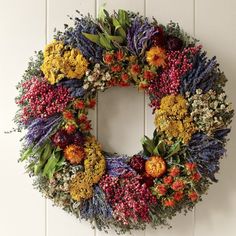 a wreath made out of dried flowers hangs on the wall next to a white door