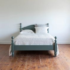 a bed sitting on top of a hard wood floor next to a white wall and wooden floors