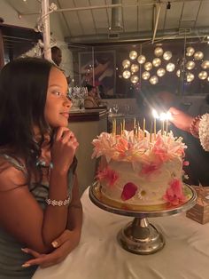 a woman sitting in front of a cake with candles on it