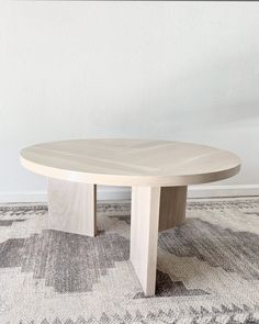 a round table with two wooden legs on a rug