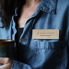 a woman is holding a cup with a name tag on her shirt that says, brown designs creative intent