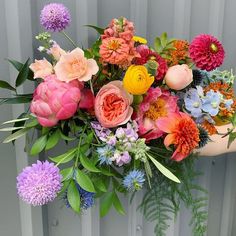 a bouquet of colorful flowers sitting on top of a wooden table next to a metal fence