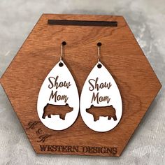 pair of earrings with the words shag mom and brown dog on them in white