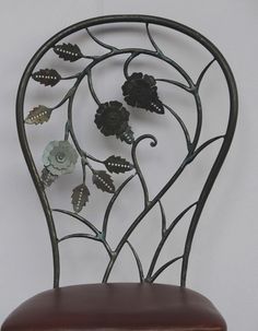 an iron chair with flowers and leaves on the backrest, against a white wall