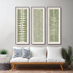 three green and white prints hanging on the wall above a couch