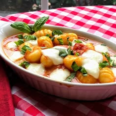 a white bowl filled with food on top of a red and white checkered table cloth