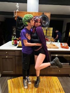 two people dressed up as batman and harley kissing each other in front of a kitchen counter