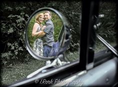 a man and woman standing in front of a car mirror