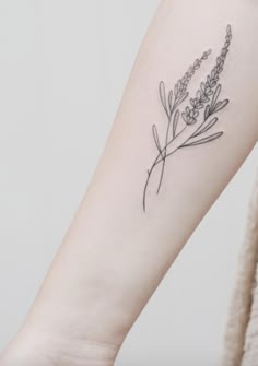 a small lavender flower tattoo on the left inner arm