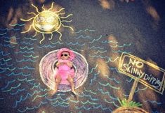 a child laying on the ground next to a chalk drawing