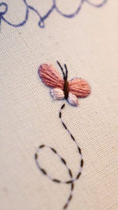 a close up of a cross stitch on a piece of cloth with a butterfly drawn on it