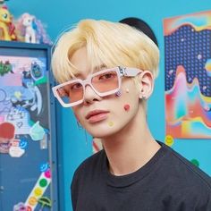 a person with some piercings on their face and wearing pink eyeliners in front of a blue wall