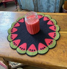 a table topped with a jar of liquid and a watermelon placemat on top of a wooden table