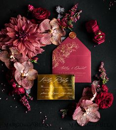 the wedding stationery is surrounded by pink flowers and gold foiled paper, along with a red envelope