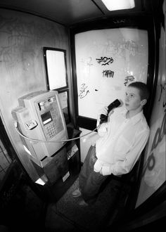 a man sitting in front of an atm machine with graffiti on the wall behind him