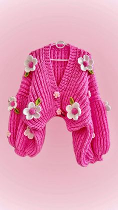 a pink cardigan with flowers on the front and back, sitting against a pink background