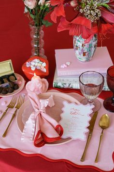 the table is set with pink and red flowers in vases, silverware, napkins, and other items