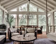 a living room filled with lots of furniture and a wooden table in the middle of it