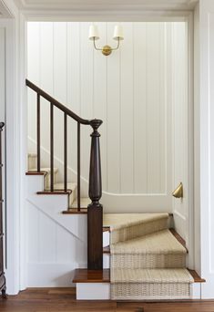 the stairs are lined with wicker baskets and wooden railings, along with two lamps on either side