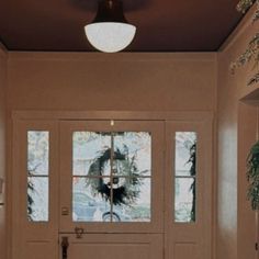 the front door to a house with two plants on either side and one plant hanging from the ceiling