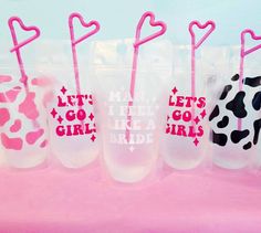 five plastic cups with straws in the shape of hearts and letters on them are lined up against a pink background