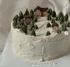 a white frosted cake with trees and houses on it