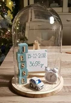 a glass clochet with a baby's birth date and toys underneath it