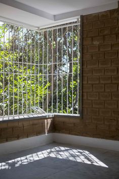 an empty room with large windows and bars on the wall, in front of trees