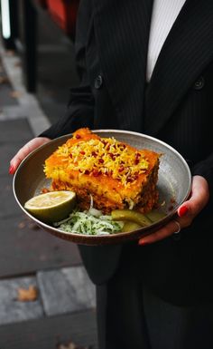 a person in a suit holding a plate with food on it and a lime slice