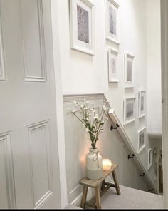 a vase filled with flowers sitting on top of a wooden stool next to a stairway