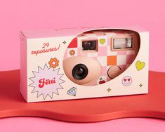 an open box with a camera inside on a pink surface