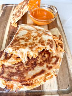 two quesadillas on a cutting board with sauce