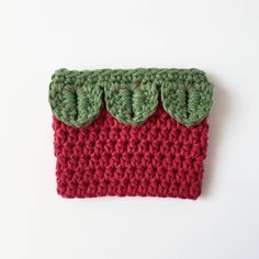 a crocheted red and green purse with three leaves on the front, sitting on a white surface