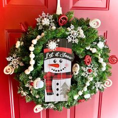 a wreath with a snowman on it hanging from the front door, decorated with christmas decorations