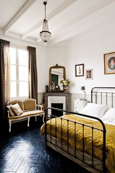 a bed room with a neatly made bed next to a chair and a mirror on the wall