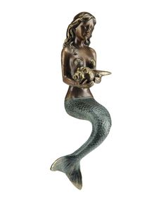 a bronze statue of a mermaid holding a fish and an egg in her hands, on a white background