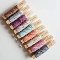 six spools of thread in different colors on wooden skewers with labels