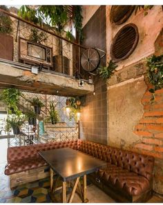 a couch and table in a room with plants on the wall above it, next to a brick wall