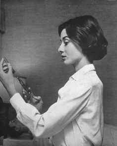 a black and white photo of a woman brushing her teeth in front of a mirror