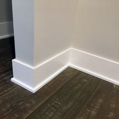 the corner of an empty room with wood flooring