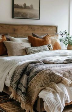 a bed with pillows and blankets on top of it next to a potted plant