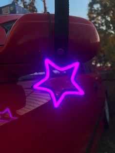 a purple star is glowing on the hood of a red car