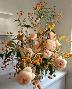 a vase filled with lots of flowers sitting on top of a counter next to a window