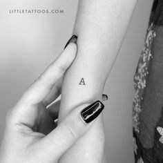 a woman's arm with a small tattoo on her left wrist and the letter a